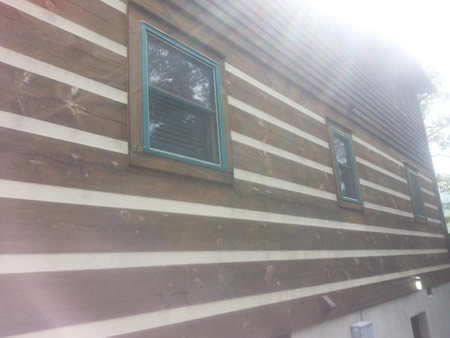 Applying elastomeric chinking to an Asheville, NC log cabin corner before winter